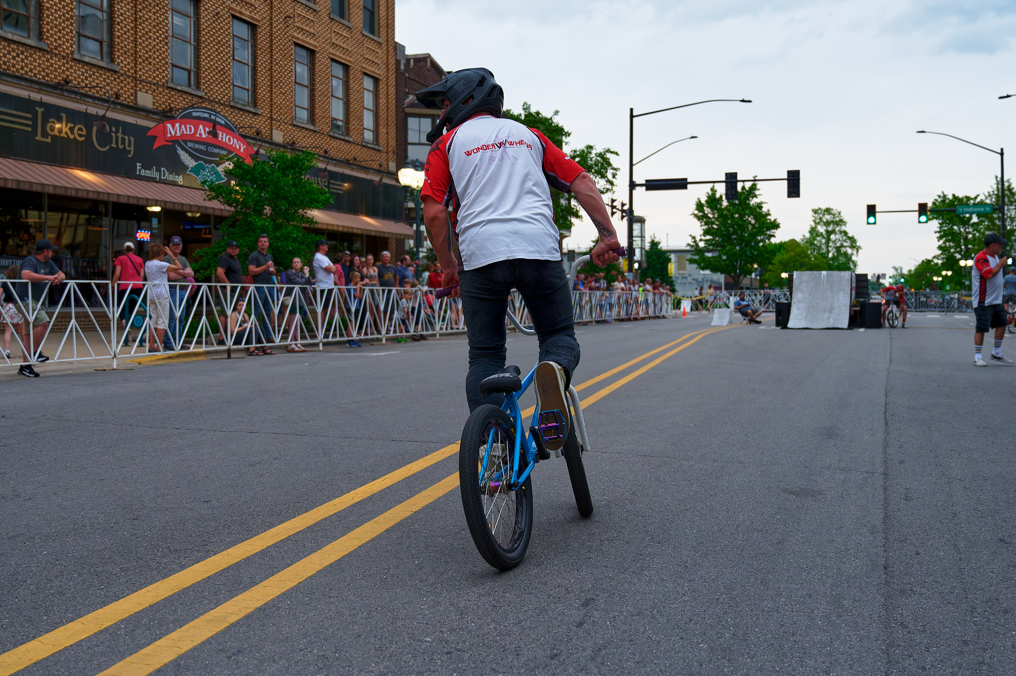 A man on his BMX bicycle prepares to race toward a ramp to perform a trick in front of a crowd.
