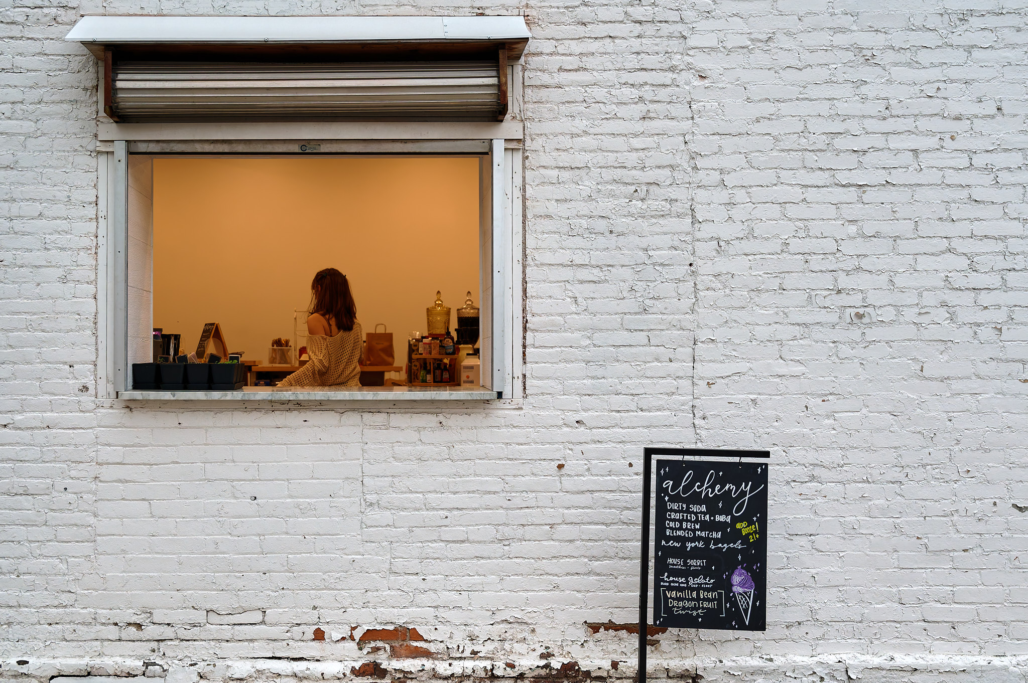 A young woman framed in a service window at a tea shop.